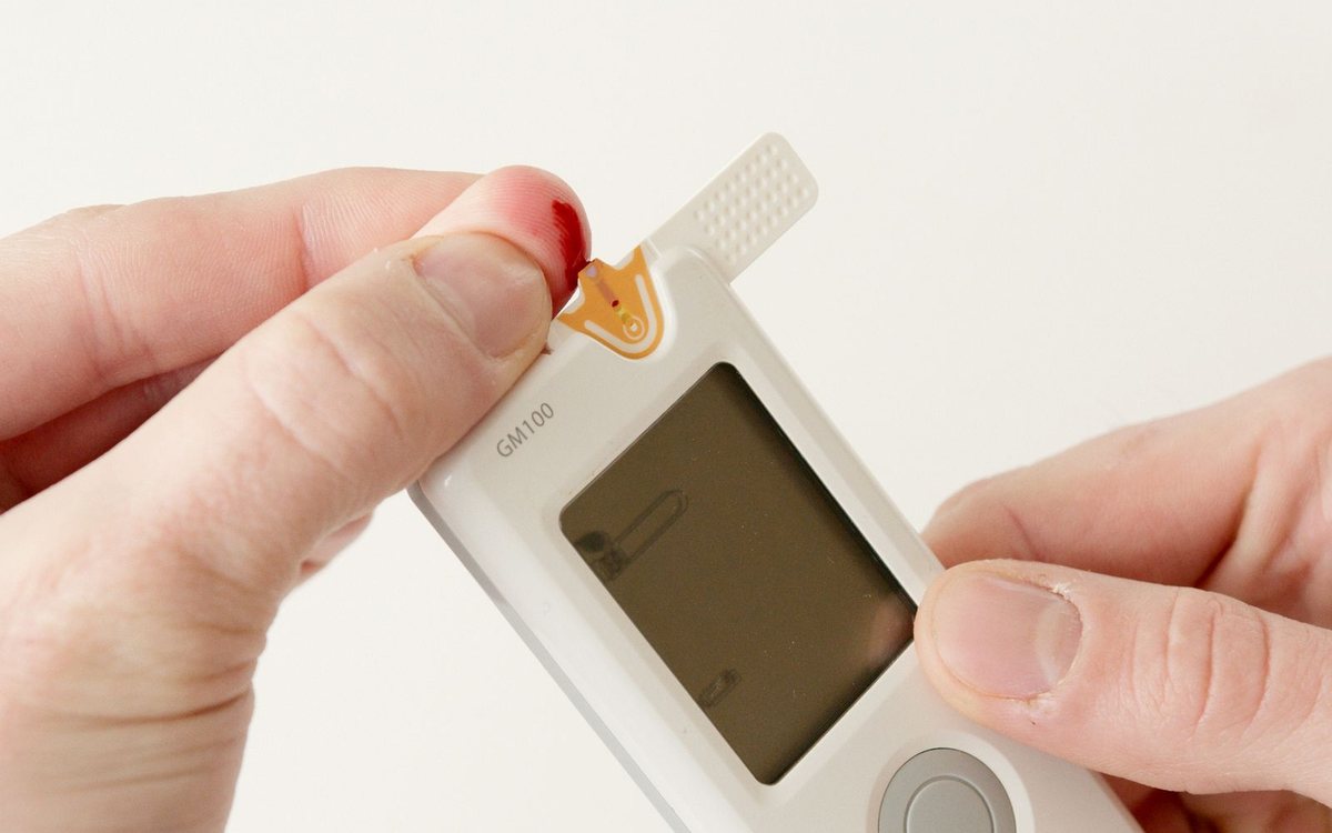 Hands using a glucometer to test blood sugar