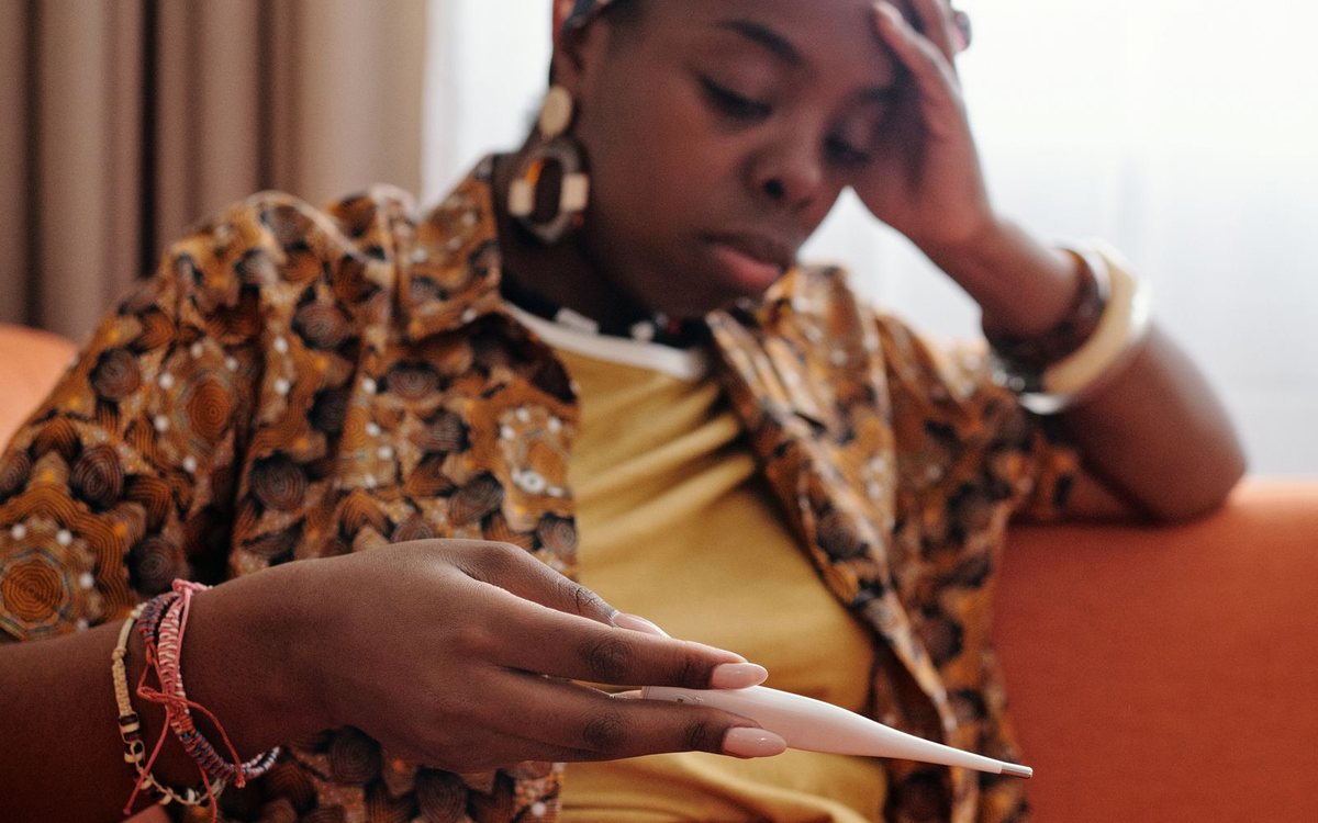 A woman checking her temperature on a couch