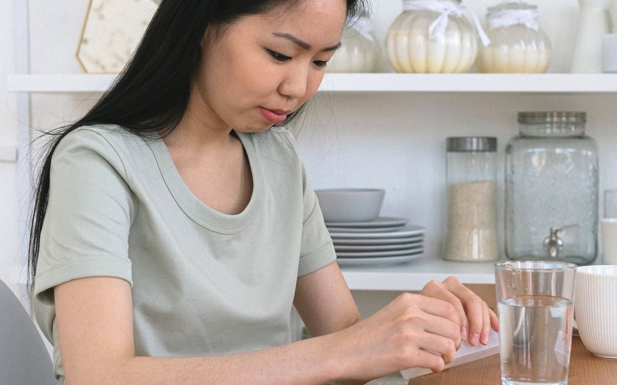 A pregnant woman taking prenatal vitamins with water