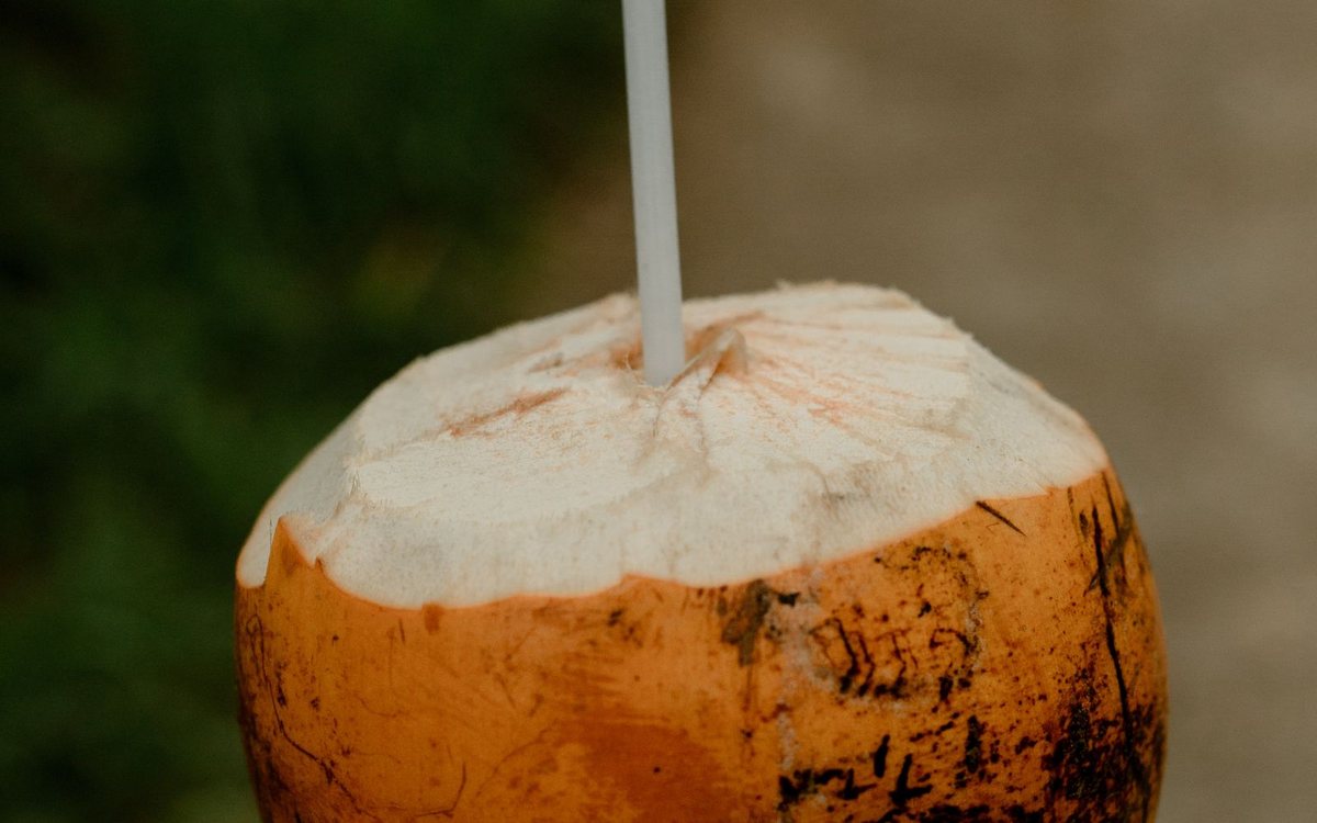 A fresh coconut with a drinking straw